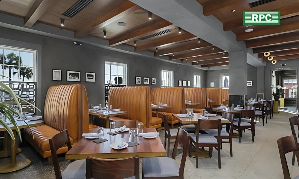 The interior of a contemporarily designed restaurant in silver and wood tones with booth seating and floor tables.