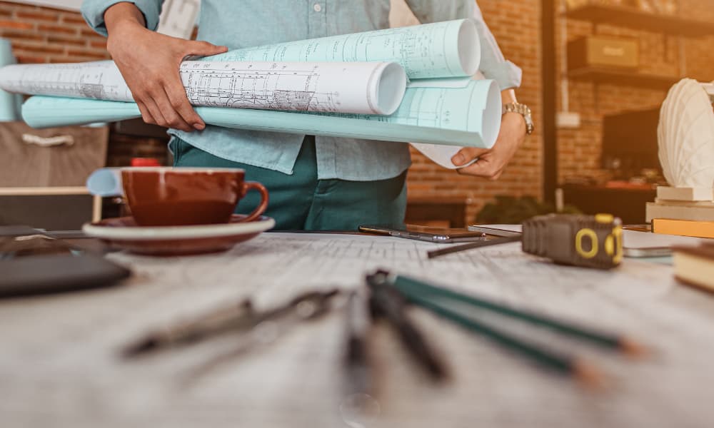 A man taking restaurant plans and blueprints to a work table.