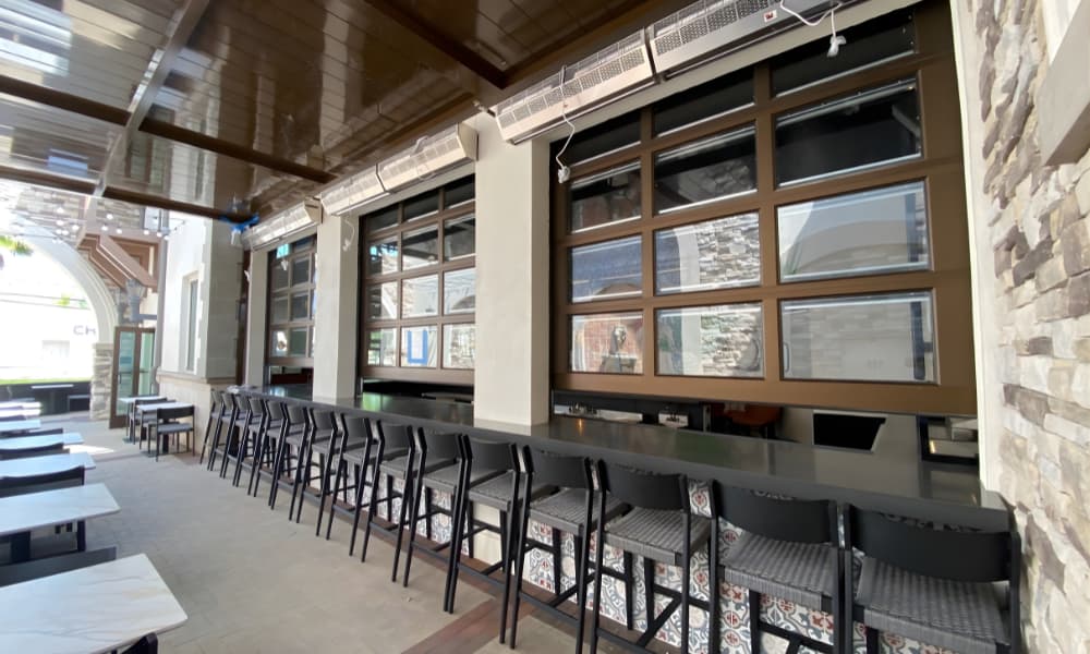 A modern restaurant exterior with outdoor seating and tables.