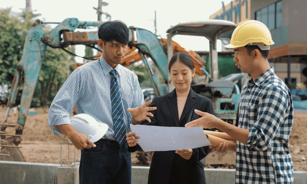 Three project team members reviewing building plans at a construction site